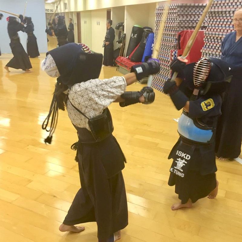Children in Kendo Gear Sparring in Gymnasium